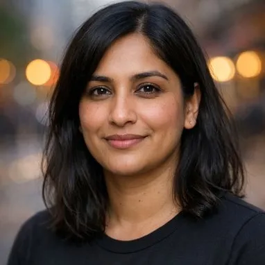Woman in late 30s, dark shoulder-length hair, calm expression, dark crew-neck top